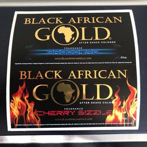 Pu&ograve; includere: Due etichette rettangolari per dopobarba Black African Gold. L'etichetta superiore riporta il testo Pressure, mentre quella inferiore mostra Cherry Sizzle con grafiche di fiamme. Entrambe includono il marchio, il sito web e 236 ml.