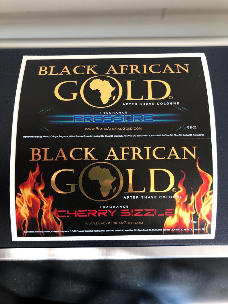Pu&ograve; includere: Due etichette rettangolari per dopobarba Black African Gold. L'etichetta superiore riporta il testo Pressure, mentre quella inferiore mostra Cherry Sizzle con grafiche di fiamme. Entrambe includono il marchio, il sito web e 236 ml.