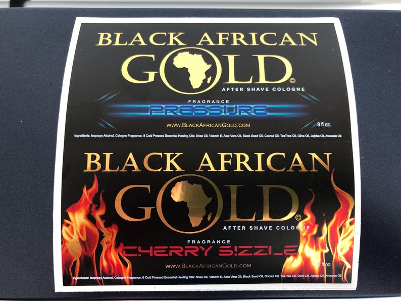 Pu&ograve; includere: Due etichette rettangolari per il dopobarba Black African Gold. L'etichetta superiore presenta la scritta Pressure con effetti di luce blu. L'etichetta inferiore mostra una grafica con fiamme e la scritta Cherry Sizzle. Entrambe elencano gli ingredienti.