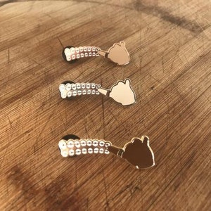 May include: Three gold-tone pins with a hand gesture design. Each pin has a row of small white beads.