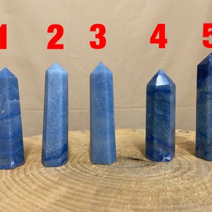 May include: Five blue crystal points, numbered 1 through 5, arranged in a row on a wooden surface.