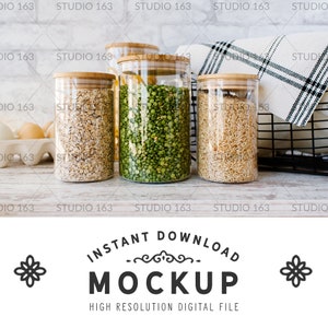 May include: Three glass jars with wooden lids filled with oats, green peas, and rice. The jars are sitting on a white wooden surface.