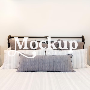 Puede incluir: Una cama con estructura de metal negro, ropa de cama blanca y varias almohadas en tonos grises y blancos. Dos lámparas con pantallas beige se encuentran sobre mesitas de noche de madera oscura. La palabra "Mockup" está superpuesta en la imagen.