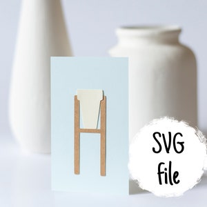 Peut inclure: Une carte bleu clair avec une découpe en papier brun d'un support de plante avec une découpe en papier blanc d'un pot. Le texte "SVG File" est sur un cercle blanc.