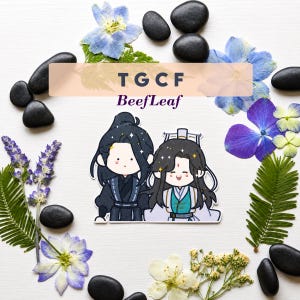 May include: A sticker featuring two cartoon characters with dark hair, one in a black outfit and one in a white and teal outfit, with the text TGCF BeefLeaf printed above them. The sticker is surrounded by blue flowers, green leaves, and black stones.