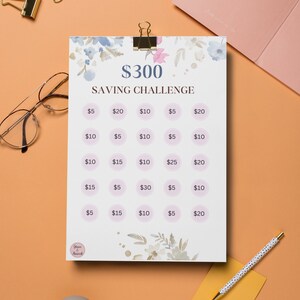 May include: A printable $300 saving challenge chart with a floral design. The chart is divided into 20 circles, each with a dollar amount listed inside. The amounts range from $5 to $30.