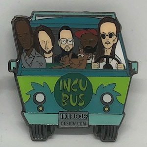 May include: A green and blue cartoon van with the words "INCU BUS" on the side. Five cartoon figures are sitting inside the van, including a dog. The van has a license plate that reads "TROUBLE CLEF DESIGN COM."