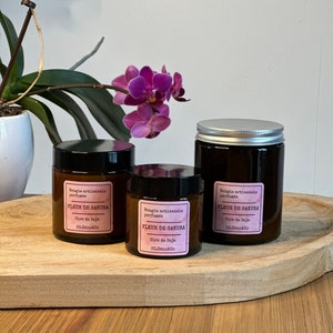 Op de afbeelding: Drie bruine glazen kaarsenpotten met zilveren deksels. De potten zijn gelabeld met "Bougie artisanale parfumée FLEUR DE SAKURA Cire de Soja 30.Déco&Co" en "Bougie artisanale parfumée FLEUR DE SAKURA Cire de Soja 80.Déco&Co".