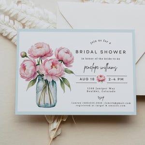 Op de afbeelding: Uitnodiging voor een bruidsdouche met een aquarel illustratie van roze pioenrozen in een pot. De uitnodiging heeft een lichtblauwe rand en bevat evenementdetails en RSVP-informatie.