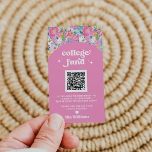 May include: A pink card with floral accents and the words "college fund" is held in a hand. The card includes a QR code and the name "Mia Williams". The background is a woven, circular placemat.