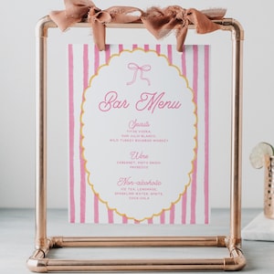May include: A copper-colored metal frame holds a pink and white striped bar menu. The menu features the words "Bar Menu" in cursive, with categories for spirits, wine, and non-alcoholic drinks. A copper mug and a bottle of liquor are in the background.