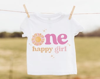May include: White t-shirt with a pink and yellow graphic that says "one happy girl" with a sun design.