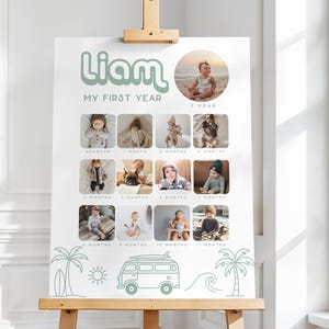 May include: A white poster on a wooden easel, displaying a baby's photo timeline. The poster has the name "Liam" in green script, with photos from 1 month to 1 year. Decorative elements include palm trees, a sun, a wave, and a van.