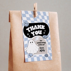 May include: A blue and white checkered thank you tag with a black speech bubble that says "Thank You". Inside the speech bubble is a white ghost with a lightning bolt and the text "for celebrating with us! love, Kelly".