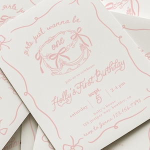 May include: A stack of light pink and white birthday invitations. The invitations feature the text "Holly's First Birthday" and "girls just wanna be one" in a decorative font. The invitations include the date, time, and location.