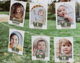 May include: A set of six white photo cards with a baby's photo on each card. The cards are strung together with twine and have a green and brown arch with a number and the word "months" on each card. The cards show the baby at different ages, from newborn to 12 months.