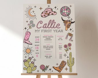 May include: A white poster with a pink and brown cowboy boot, a cactus, a sun, and a moon. The poster says "Callie My First Year" and lists her height, weight, and other milestones.