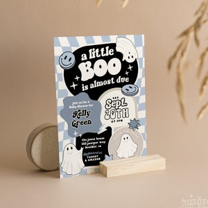May include: A blue and white baby shower invitation with a ghost and the text "a little BOO is almost due". The invitation is for Kelly Green and is scheduled for September 20th at 3 PM. The address is 122 Juniper Way, Boulder, CO. The invitation also includes a note about registering at Target and Amazon.