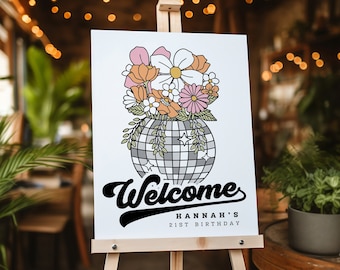 May include: A welcome sign with a disco ball vase filled with colorful flowers. The sign reads "Welcome" in a retro font and "Hannah's 21st Birthday" in a smaller font.