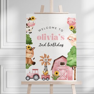 Könnte beinhalten: Willkommen zu Olivias 2. Geburtstagsschild mit einem rosa Scheunen, Bauernhoftieren und einem Traktor. Das Schild steht auf einem Holzstaffelei.