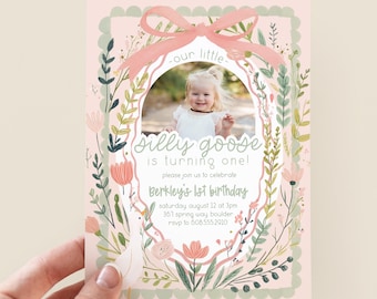 May include: A pink birthday invitation with a photo of a child in an oval frame, surrounded by floral illustrations and a pink ribbon. The text reads "Silly Goose is turning one!" and details for the party.