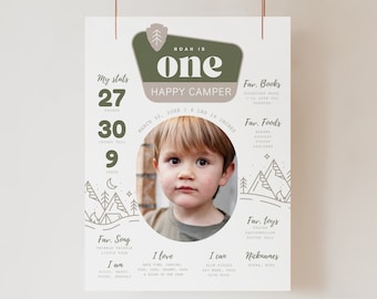 Peut inclure: Une affiche illustrée verte et marron avec une photo d'un enfant. L'affiche indique "Noah a un an, heureux campeur" et comprend les statistiques de l'enfant : 27 livres, 30 pouces de haut et 9 dents. L'affiche liste également les livres, aliments, jouets, chansons et surnoms préférés de l'enfant.