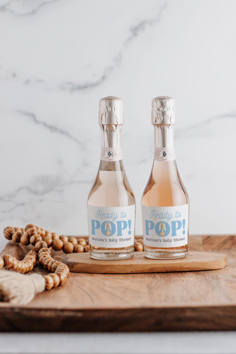 May include: Two mini bottles of champagne with blue and white labels that say "Ready to POP!" and "Marissa's Baby Shower".