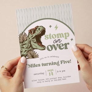 Puede incluir: Una tarjeta de invitaci&oacute;n de cumplea&ntilde;os rectangular con un T-Rex verde con gafas de sol rojas, hojas de palma y el texto: Stomp on over, join us to celebrate, Miles turning Five, Saturday Sept 14, 2-4 pm, niles' house, 123 juniper way, boulder, rsvp to kelly at 123.456.7890.
