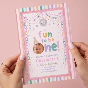 K&ouml;nnte beinhalten: Eine rechteckige Geburtstagseinladungskarte mit rosa gewelltem Rand und vertikalen Pastellstreifen. Das Design zeigt eine Discokugel, h&auml;ngende Ketten, Sterne und den Text: it's fun to be one! Join us to celebrate Charlotte's first birthday.