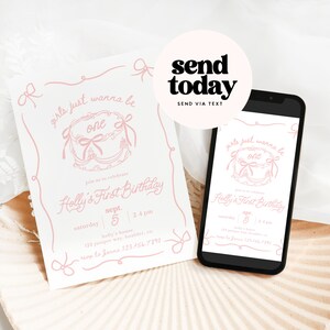 May include: A white invitation and a smartphone displaying a first birthday party invitation. The invitation features pink text and a cake graphic with the words "girls just wanna be one." The phone is black with a white background.