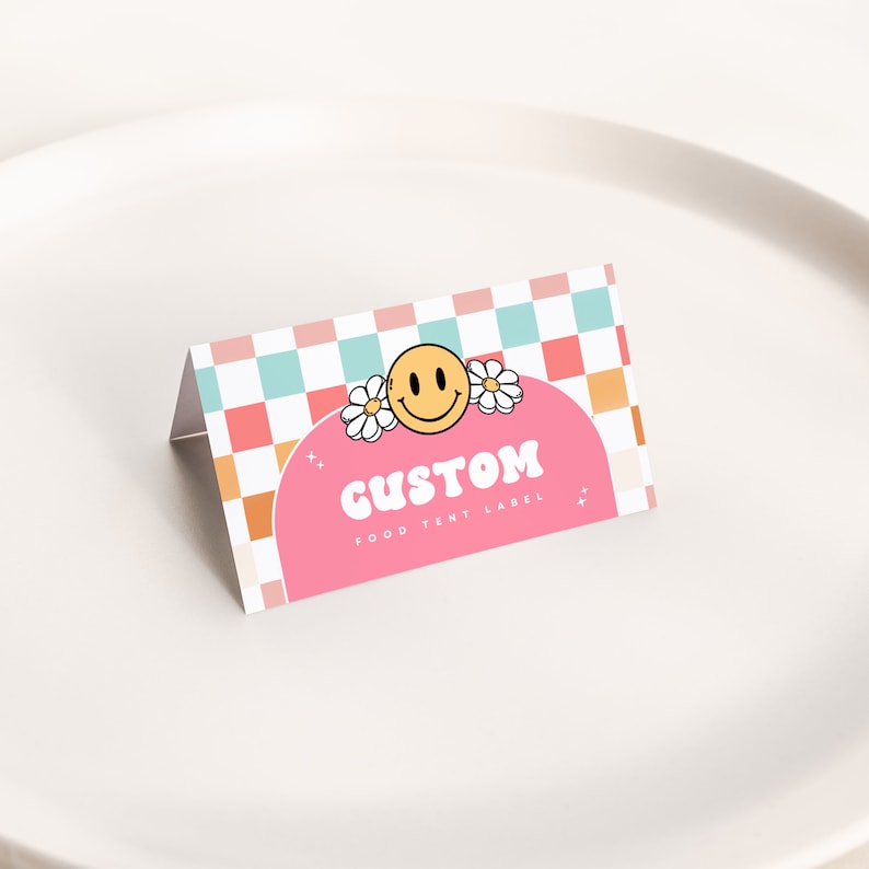 May include: Pink and orange food tent label with a checkered background. The label features a smiling face with flowers and the text "CUSTOM FOOD TENT LABEL".