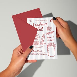 K&ouml;nnte beinhalten: Ein roter Umschlag mit einer Einladung zu einem Seafood Boil. Die Einladung hat einen wei&szlig;en Hintergrund mit blauen vertikalen Streifen und roten Illustrationen von Meeresfr&uuml;chten und dem Text "PLEASE JOIN US FOR A Seafood Boil".