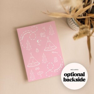May include: A pink card with white illustrations of camping elements, including teepees, trees, and a campfire. The text "happy camp way" and "pincusue path" are written on the card. A white circle with the text "optional backside" is also present.