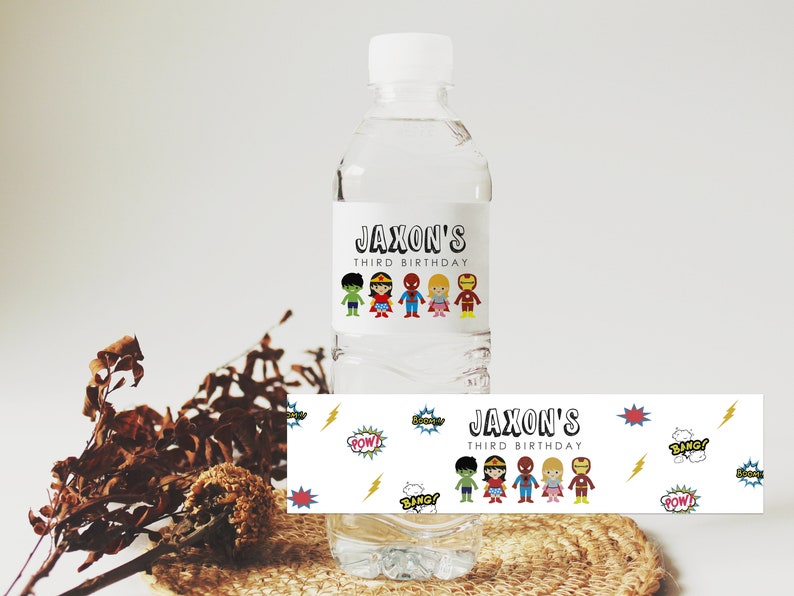 May include: Water bottle label with a superhero theme. The label features a white background with colorful cartoon superheroes, the text "Jaxon's Third Birthday", and comic book sound effects like "Pow!" and "Bang!"
