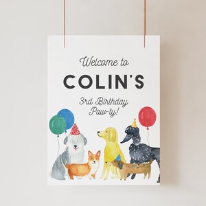 May include: Welcome to Colin's 3rd Birthday Paw-ty! A white sign with black text and colorful illustrations of dogs wearing party hats and holding balloons.