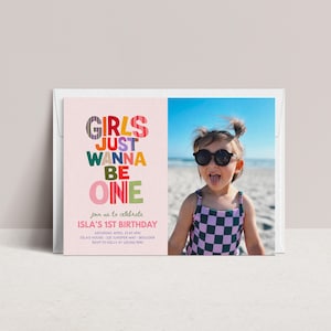May include: A rectangular birthday invitation card featuring a light pink background with the colorful text "GIRLS JUST WANNA BE ONE" and event details. Beside the text is a photograph of a child wearing black sunglasses and a purple and black checkered swimsuit.
