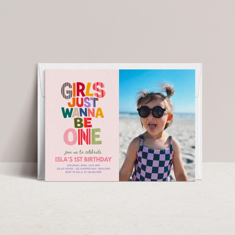 May include: A rectangular birthday invitation card featuring a light pink background with the colorful text "GIRLS JUST WANNA BE ONE" and event details. Beside the text is a photograph of a child wearing black sunglasses and a purple and black checkered swimsuit.
