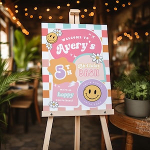 May include: A pink and orange welcome sign with a checkered background. The sign says "Welcome to Avery's 5th Birthday Bash". There are smiley faces and flowers on the sign.