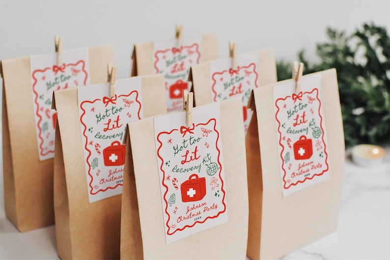 Puede incluir: Un conjunto de seis bolsas de papel marr&oacute;n con etiquetas rojas y verdes "Got too Lit Recovery Kit". Las etiquetas muestran un botiqu&iacute;n de primeros auxilios rojo con una cruz blanca y ramas de acebo verdes.