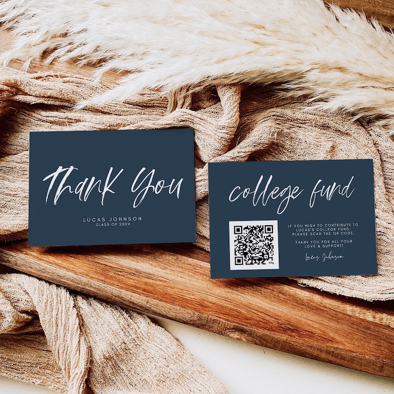 May include: Two navy blue cards with white script. One card reads "Thank You" and the other says "college fund" with a QR code. The cards are on a wooden surface with a beige fabric.