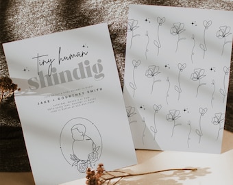 May include: A white baby shower invitation with black text that reads "Tiny human shindig" and includes the names "Jake + Courtney Smith". The invitation has a simple line drawing of a baby in a circle with flowers.