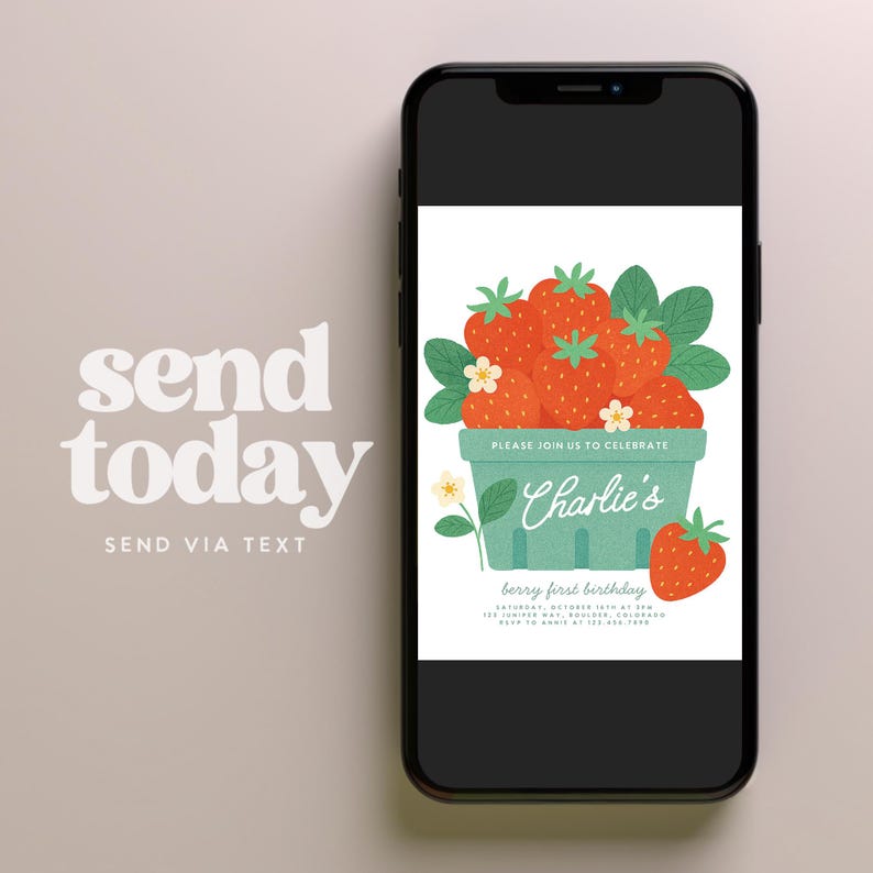 May include: A smartphone displays a birthday invitation with a berry theme. The invitation features a green basket overflowing with red strawberries, green leaves, and white flowers. The text reads "Charlie's berry first birthday."