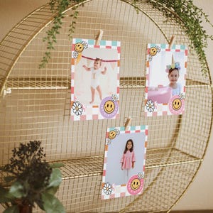 May include: Three pink and yellow photo cards with smiley faces and flowers are displayed on a gold wire rack. Each card has a photo of a child with the text "1st Birthday" on the bottom.