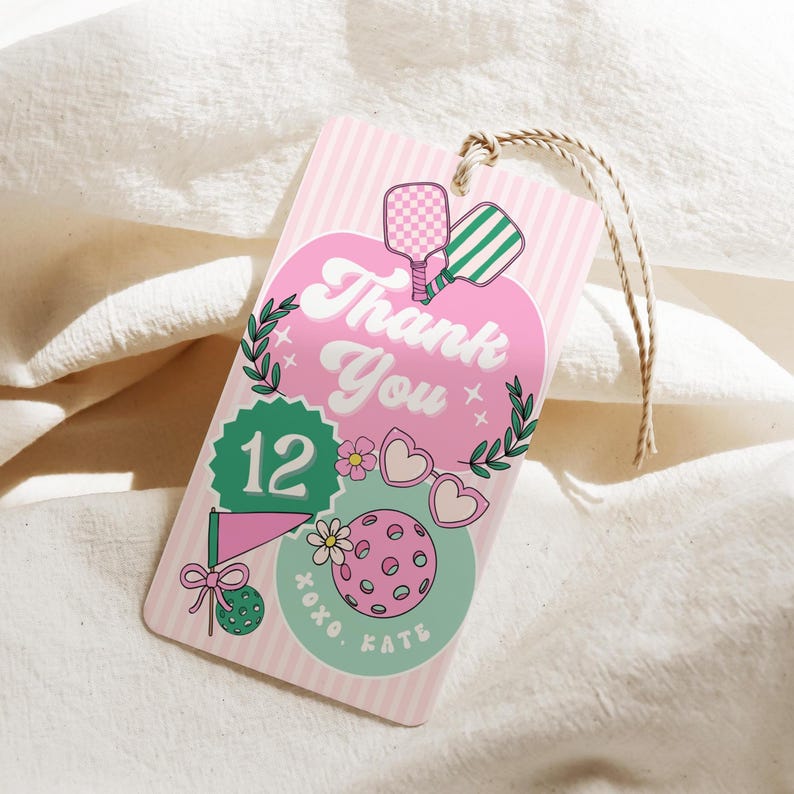 May include: Pink and white striped gift tag with a pickleball theme. The tag features the words "Thank You" in a retro font, along with pickleball paddles, a pickleball, and the number 12. A twine string is attached.