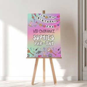 Puede incluir: Un letrero de fiesta colorido sobre un caballete de madera. El letrero presenta el texto "In My Birthday Era" y "VIP Entrance Sophie's Par-tay" en una fuente divertida. Los elementos decorativos incluyen notas musicales, guitarras y botas de vaquero.