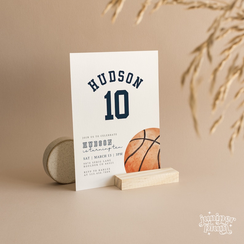May include: A white invitation card with blue and black text that reads "HUDSON is turning ten" and "JOIN US TO CELEBRATE HUDSON 10". The invitation also includes the date, time, and location of the event. A watercolour illustration of a basketball is in the bottom right corner of the card.