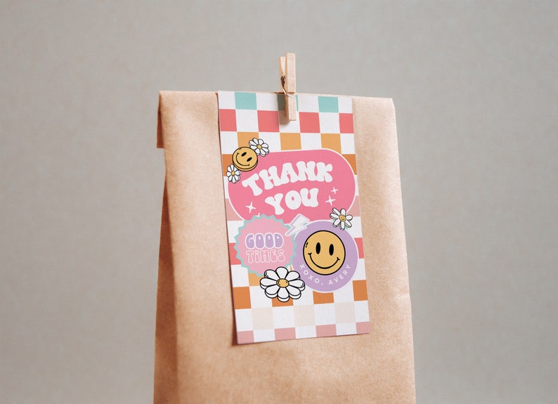 May include: A pink and orange thank you tag with a checkered background. The tag features a pink circle with the text "Thank You" in white. There are also smiley faces, flowers, and the text "Good Times" in a purple circle.