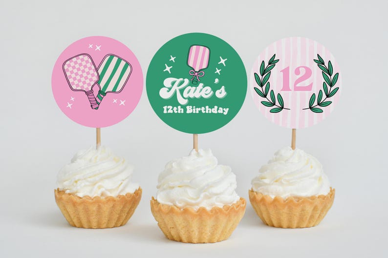 May include: Three cupcakes with white frosting, each topped with a decorative circle. One pink circle features pickleball paddles, another green circle says "Kate's 12th Birthday", and the last has a pink "12" with a green wreath.