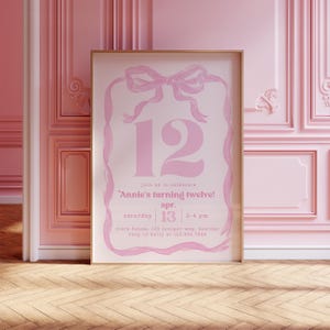 May include: A framed pink invitation with a bow and ribbon design. The number 12 is prominently displayed, with text that reads "Annie's turning twelve!" and details for the event, including the date, time, and location.