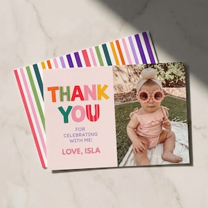 May include: A rectangular thank you card featuring a light pink background with the text THANK YOU FOR CELEBRATING WITH ME! LOVE, ISLA in colorful letters. The card includes a photo of a child wearing a pink outfit and flower-shaped sunglasses.
